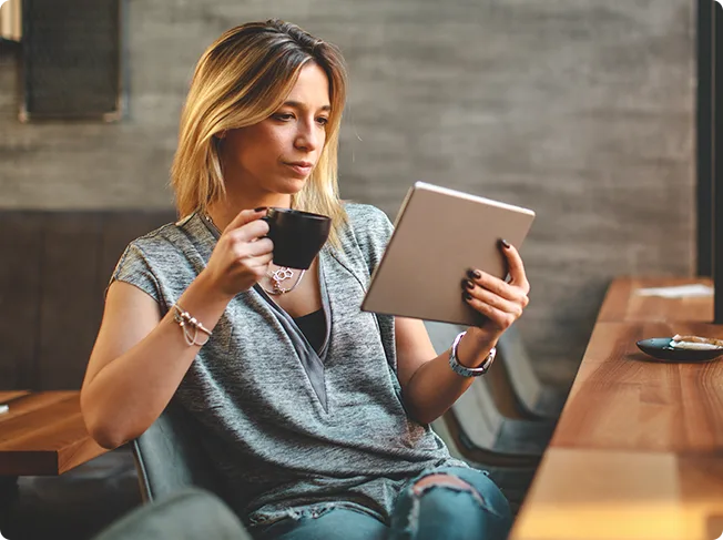 Woman reviewing content on a tablet with coffee