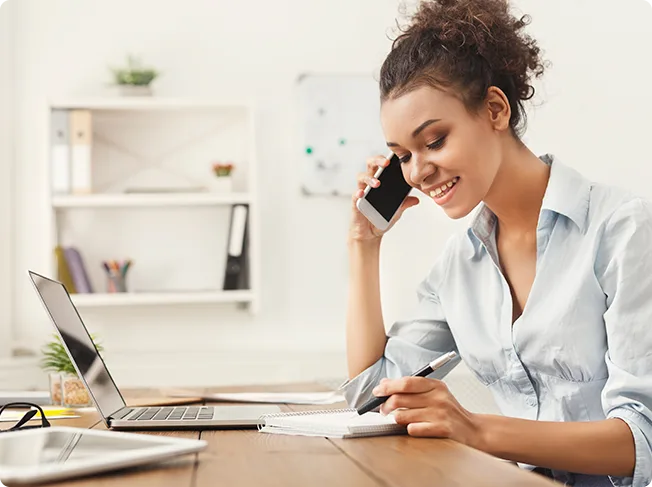 Marketer on the phone taking notes at her desk